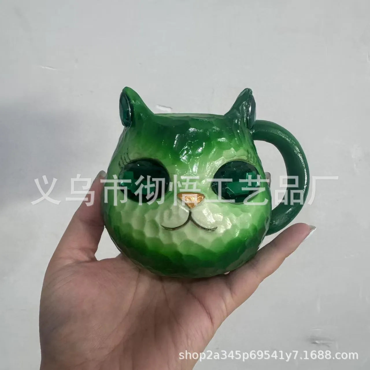 Colourful cat-shaped resin craft ornament in purple, green, blue, or pink on a desk.