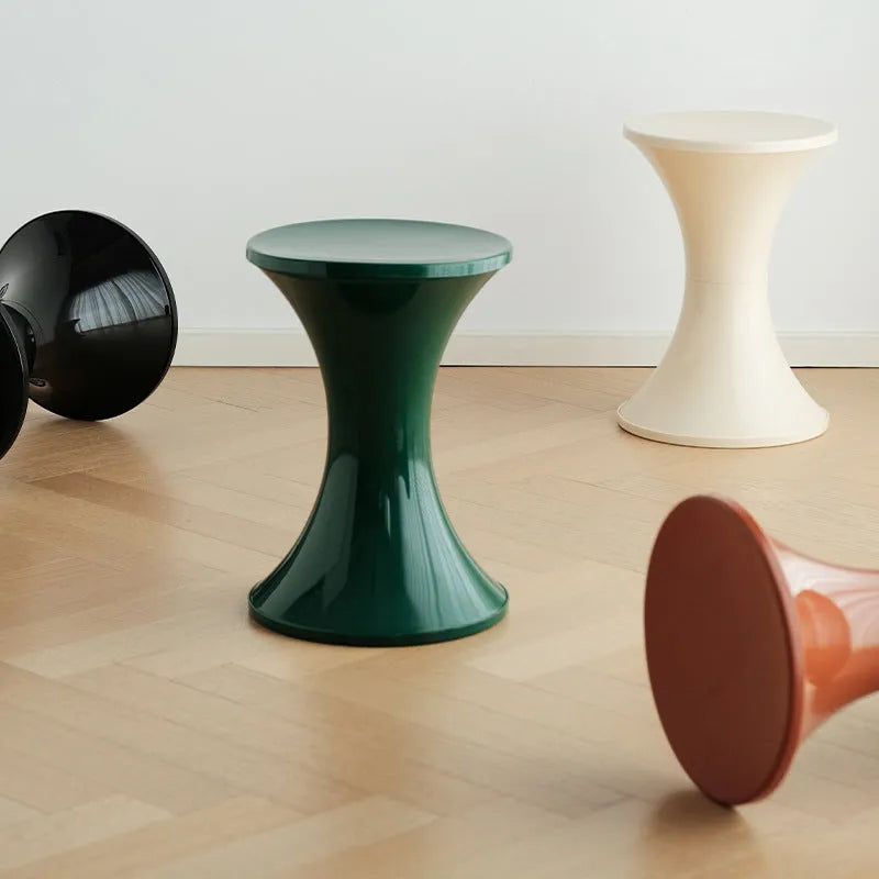 Plastic hourglass-shaped shoe changing stool in selected colour, shown in a home entryway setting.