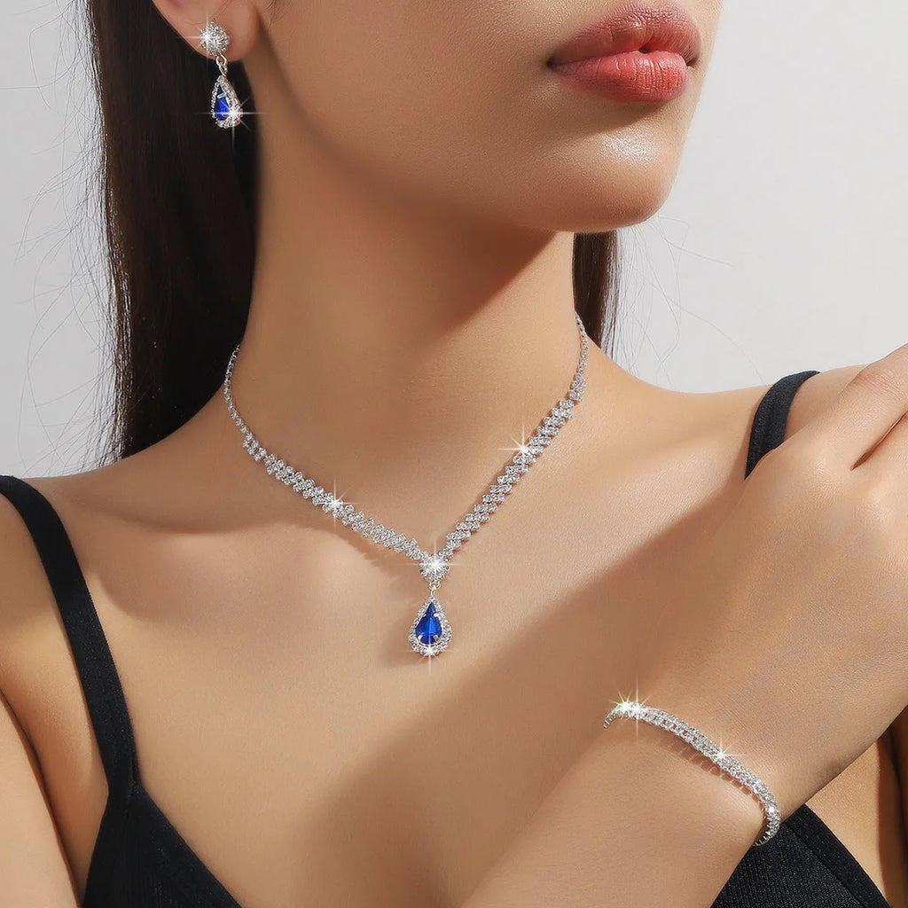 Rhinestone drop pendant necklace and matching earrings with geometric claw chain, shown in blue.