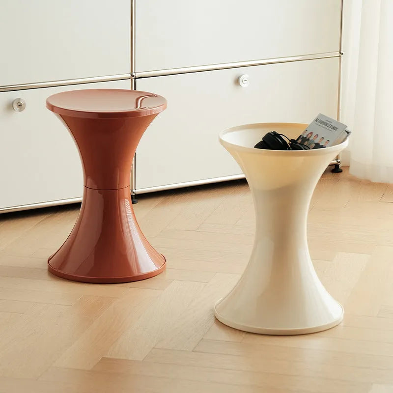 Plastic hourglass-shaped shoe changing stool in selected colour, shown in a home entryway setting.