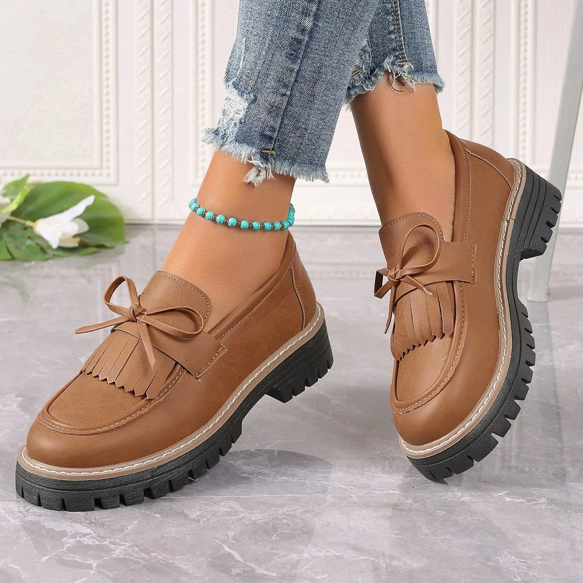 Black plus size women's loafers with a tassel and bowknot decoration on the low-cut upper.
