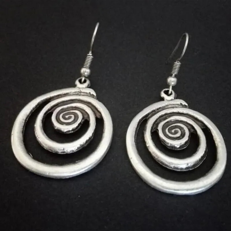Silver geometric spiral earrings with distressed finish on white background
