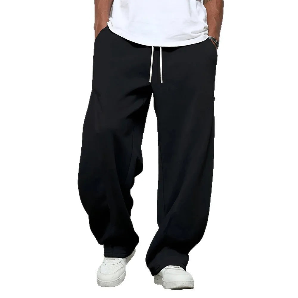 Men's straight leg casual trousers in black with a drawstring waist, laid flat.