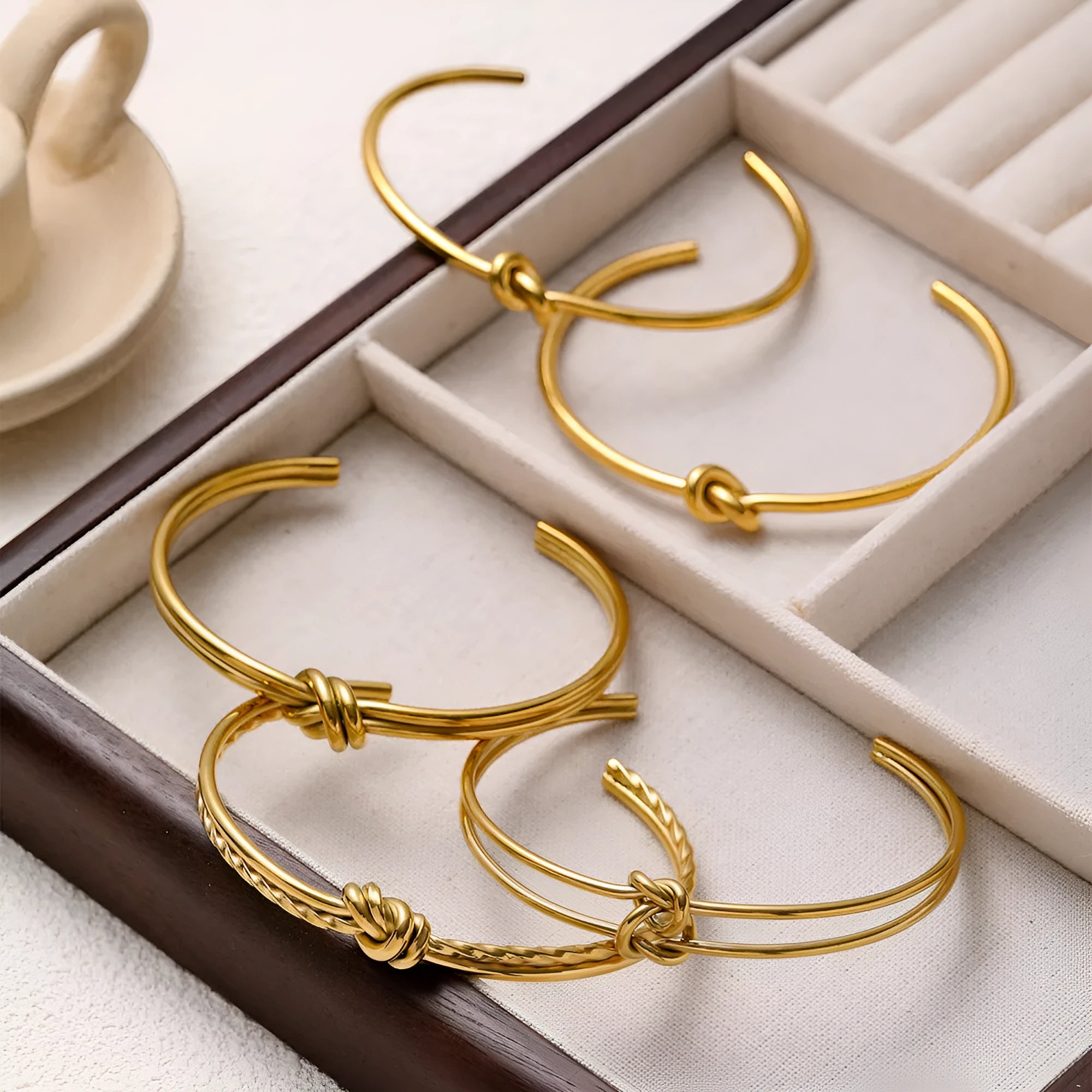 Women's stainless steel knotted C-shaped open double-layer bracelet in gold or silver tone.