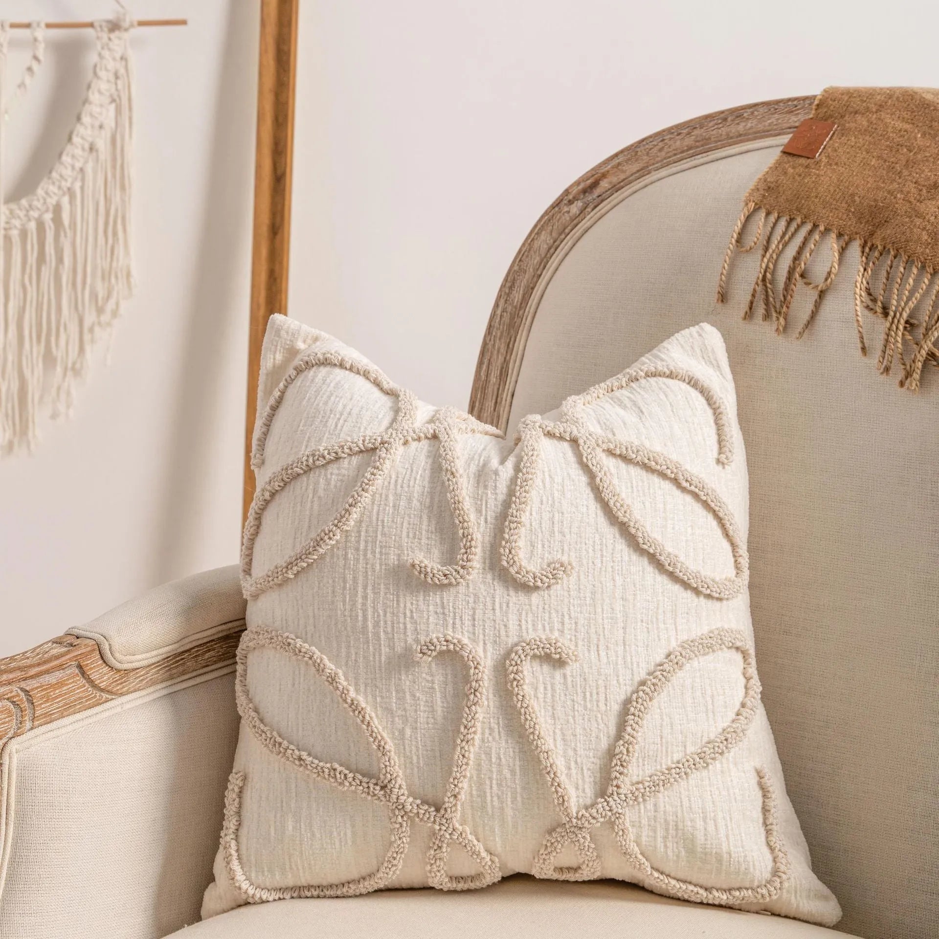 Knitted cushion cover with tassel fringe in a patterned design, shown on a sofa.