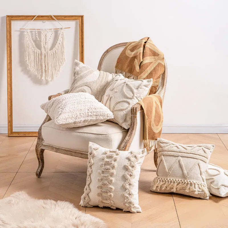 Knitted cushion cover with tassel fringe in a patterned design, shown on a sofa.