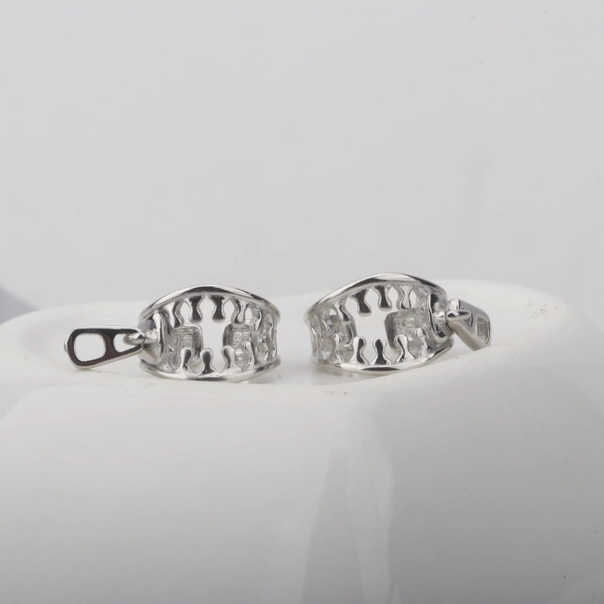 A pair of geometric copper clip-on earrings with a zip pull detail, in colour ES862, showing the bone clip fastening.
