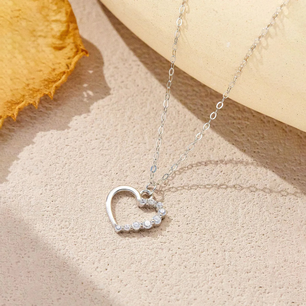 Sterling silver hollow heart and circle pendant necklace on a regular chain, shown in a gold tone finish.