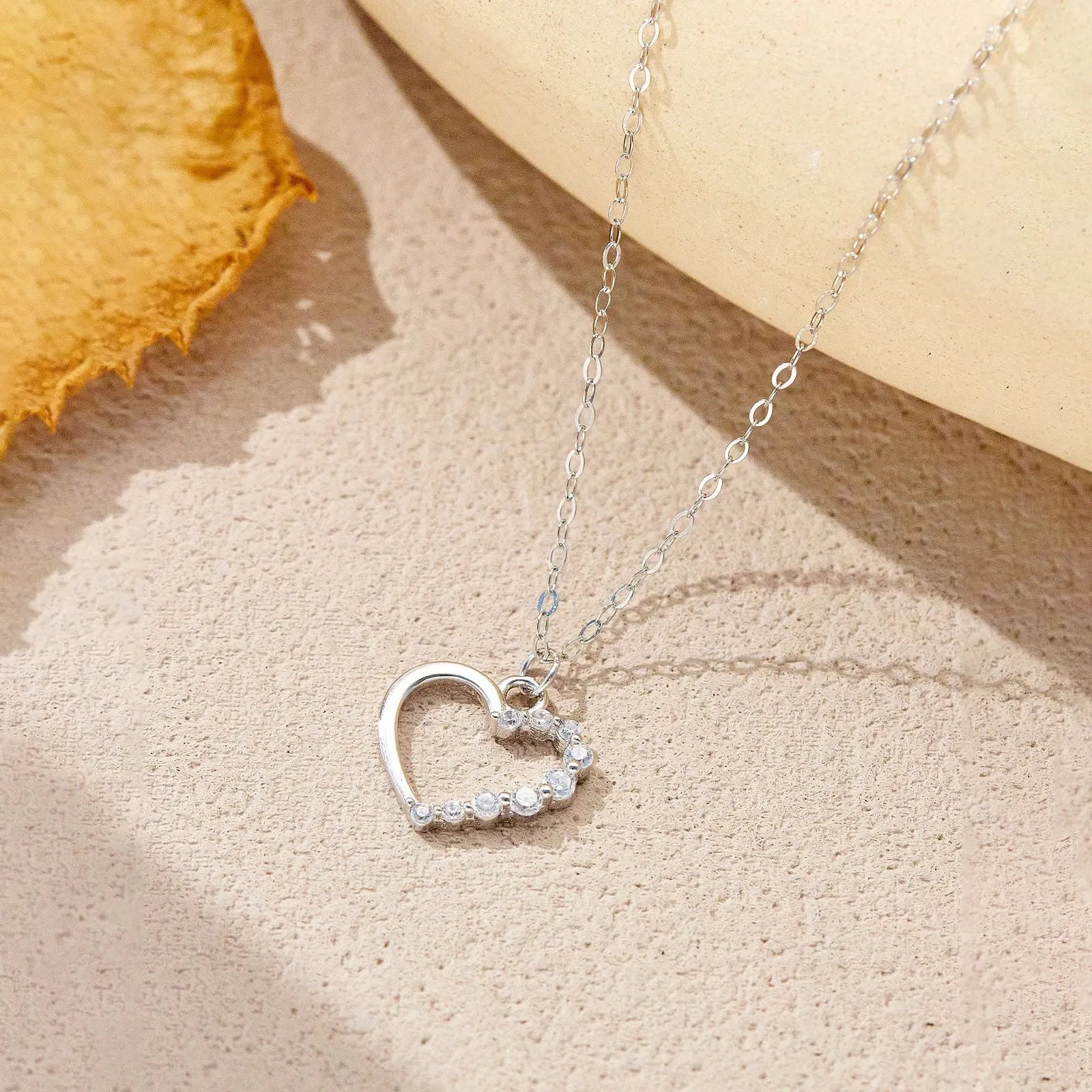 Sterling silver hollow heart and circle pendant necklace on a regular chain, shown in a gold tone finish.