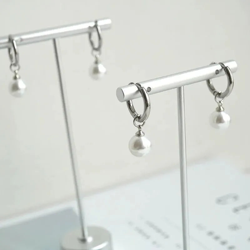 A pair of women's geometric round pearl drop earrings with a titanium steel finish and alloy construction.