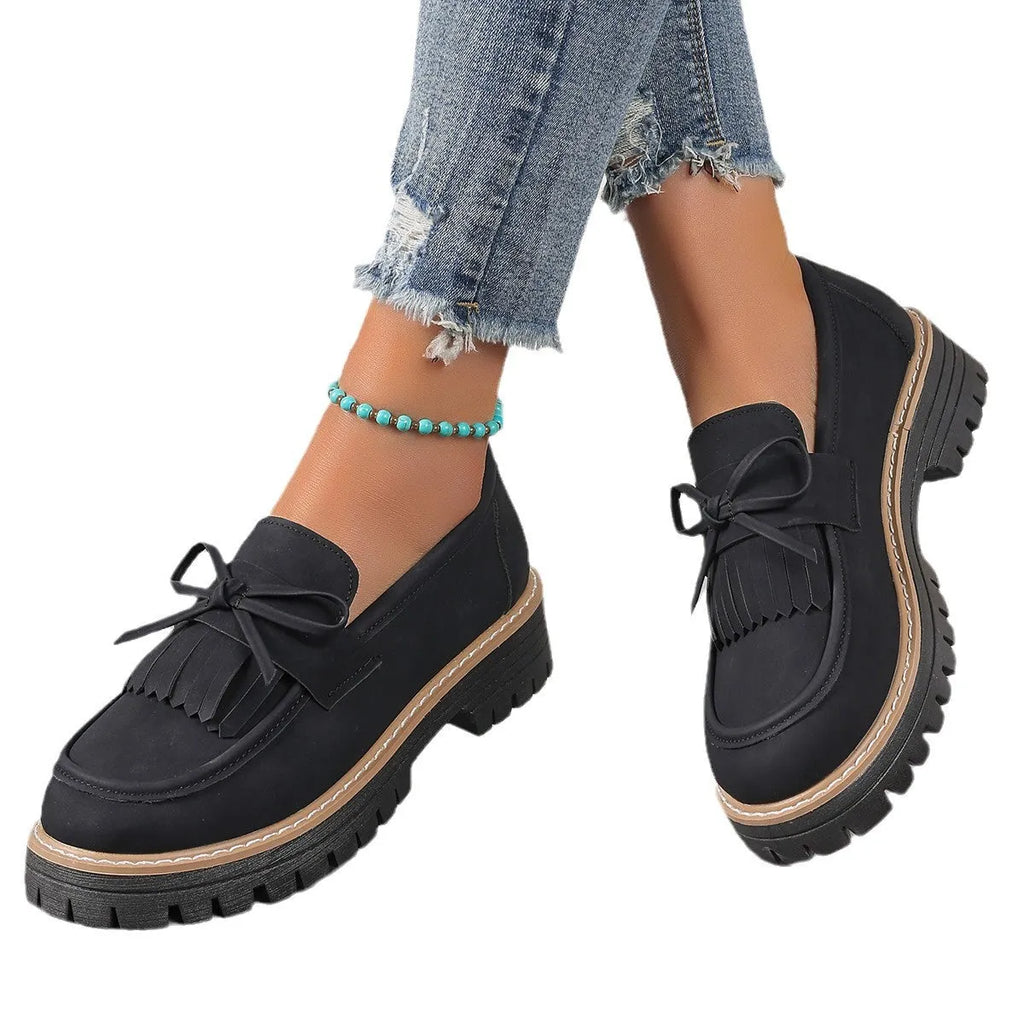 Black plus size women's loafers with a tassel and bowknot decoration on the low-cut upper.