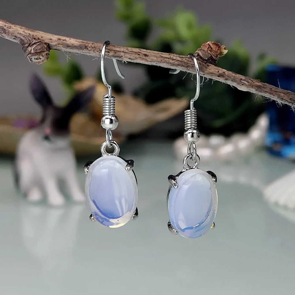 A pair of alloy drop earrings with a moonlight opal electroplated finish and a retro cross design within an ellipse shape.