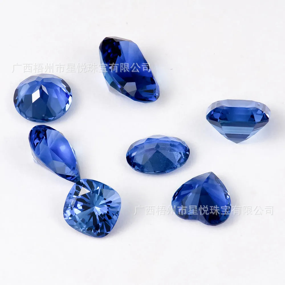 Royal blue loose gemstone in heart, round, and pear shapes on a white background.