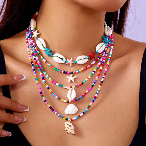 Five-piece women's necklace set with blue electroplated starfish, shell, and conch bead pendants on adjustable alloy chains.