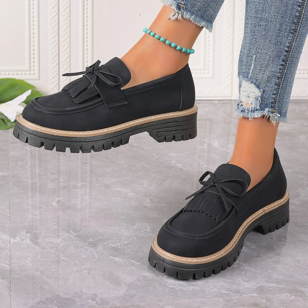 Black plus size women's loafers with a tassel and bowknot decoration on the low-cut upper.