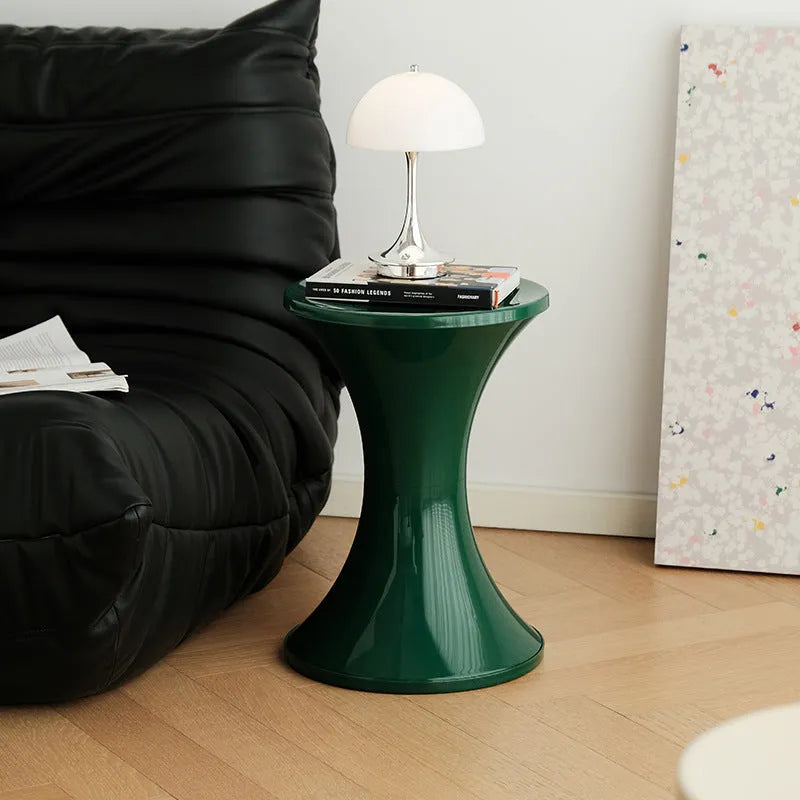 Plastic hourglass-shaped shoe changing stool in selected colour, shown in a home entryway setting.