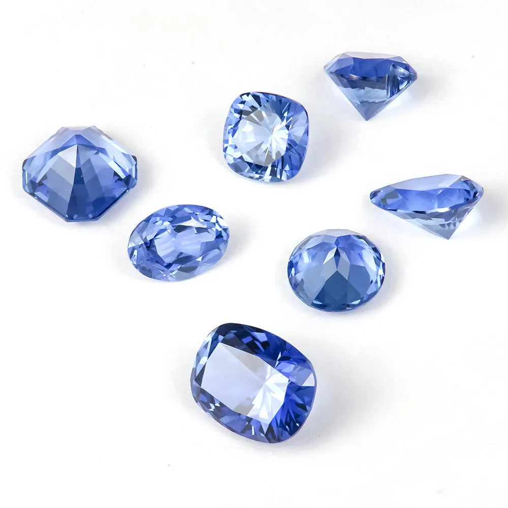 Royal blue loose gemstone in heart, round, and pear shapes on a white background.