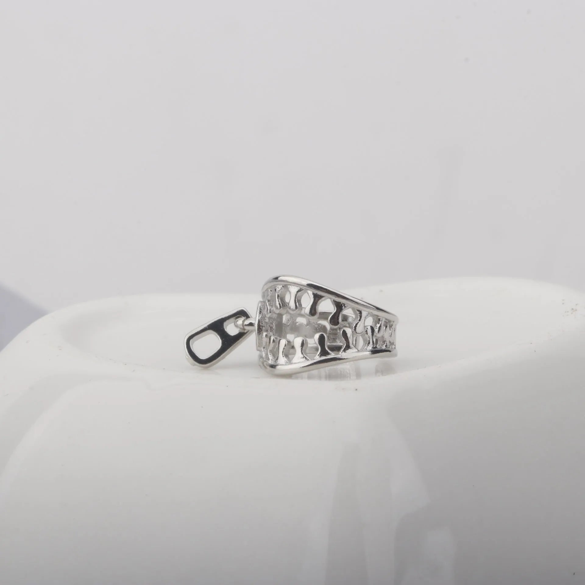 A pair of geometric copper clip-on earrings with a zip pull detail, in colour ES862, showing the bone clip fastening.