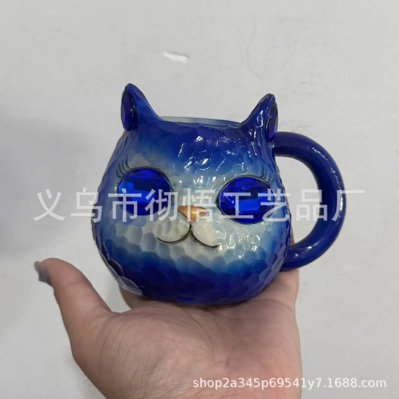 Colourful cat-shaped resin craft ornament in purple, green, blue, or pink on a desk.