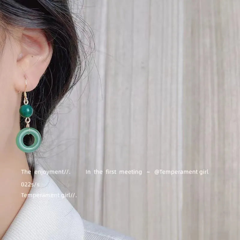 Green geometric peace buckle shape earrings with jade design on zinc alloy background
