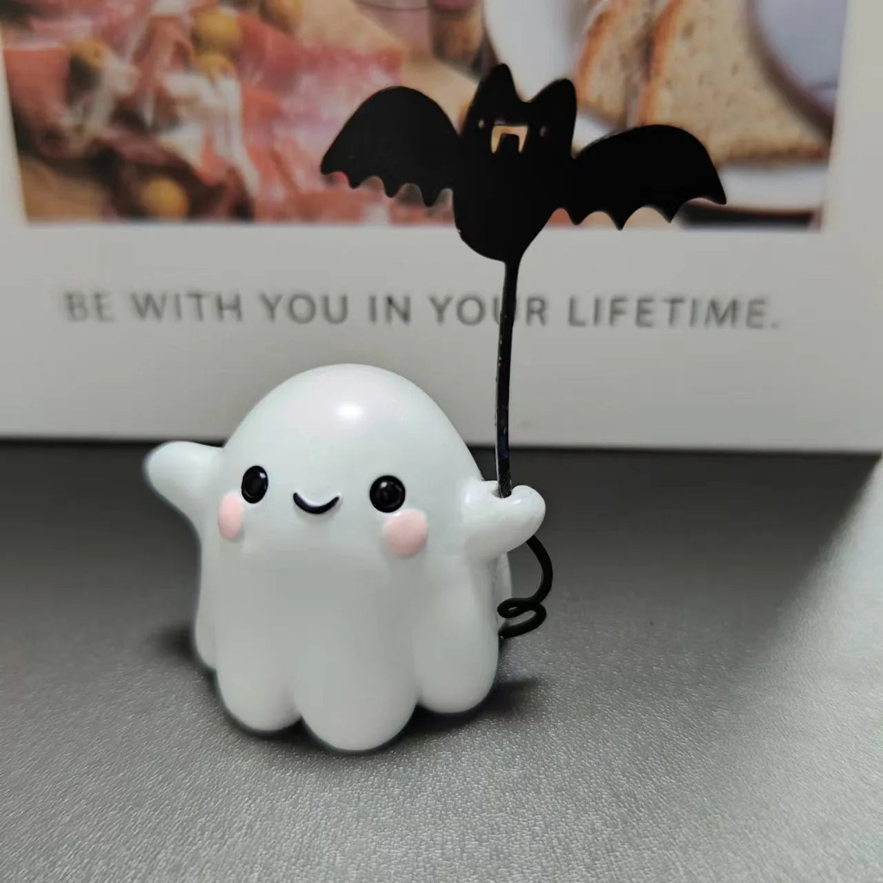 Mini ghost walking dog Halloween statue holding a bat, resin figurine on white background.