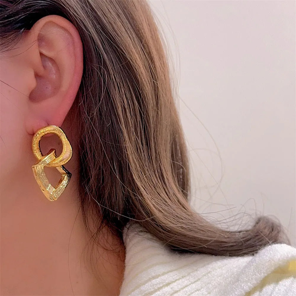 A pair of geometric circle drop earrings with a gold electroplated finish, showing a 3.4cm pendant length.