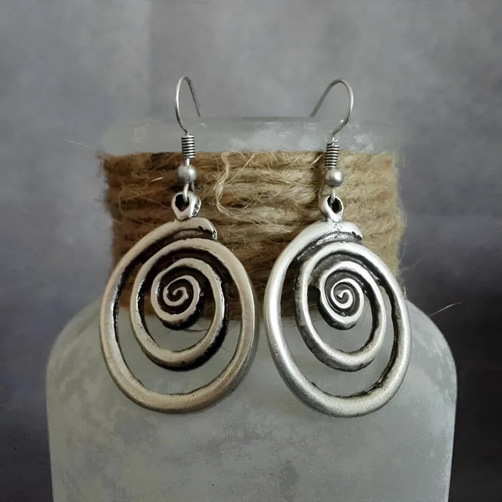 Silver geometric spiral earrings with distressed finish on white background