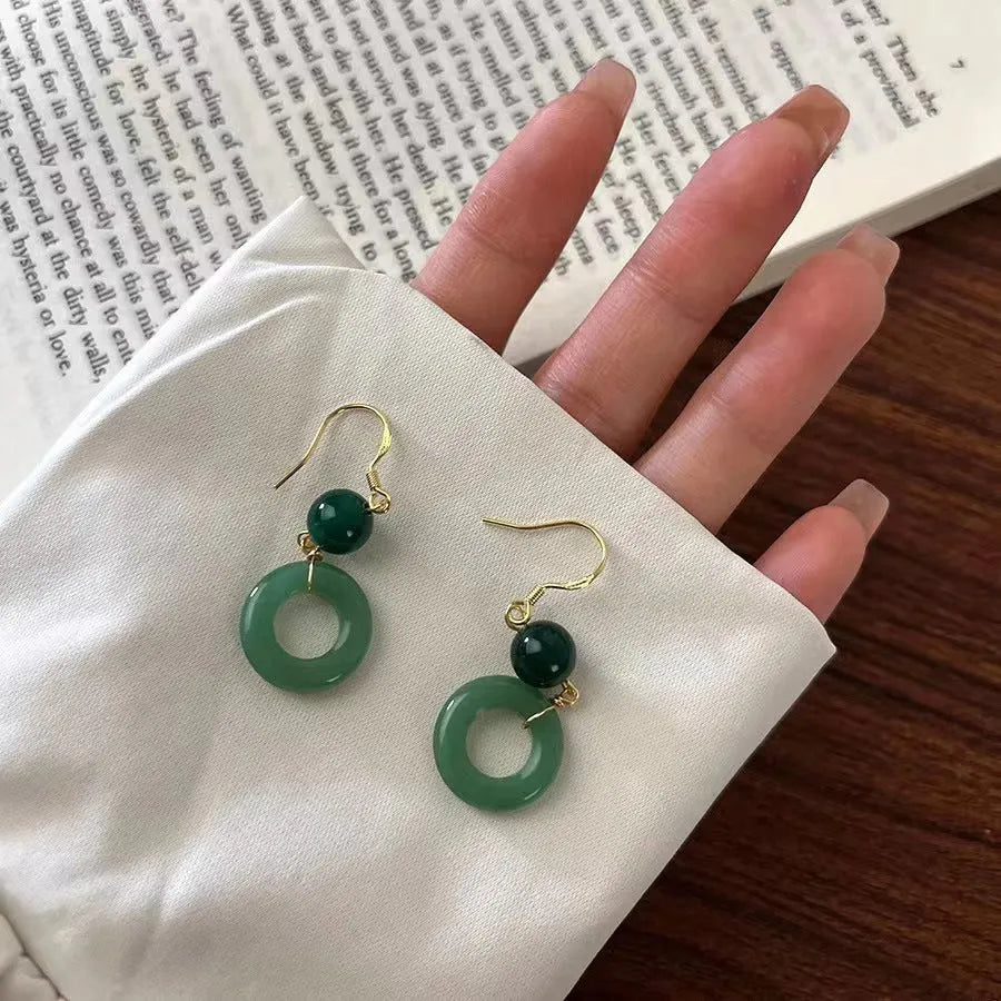 Green geometric peace buckle shape earrings with jade design on zinc alloy background