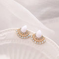 Close-up of silver retro fan-shaped earrings with opal and rhinestone decoration on a needle post.