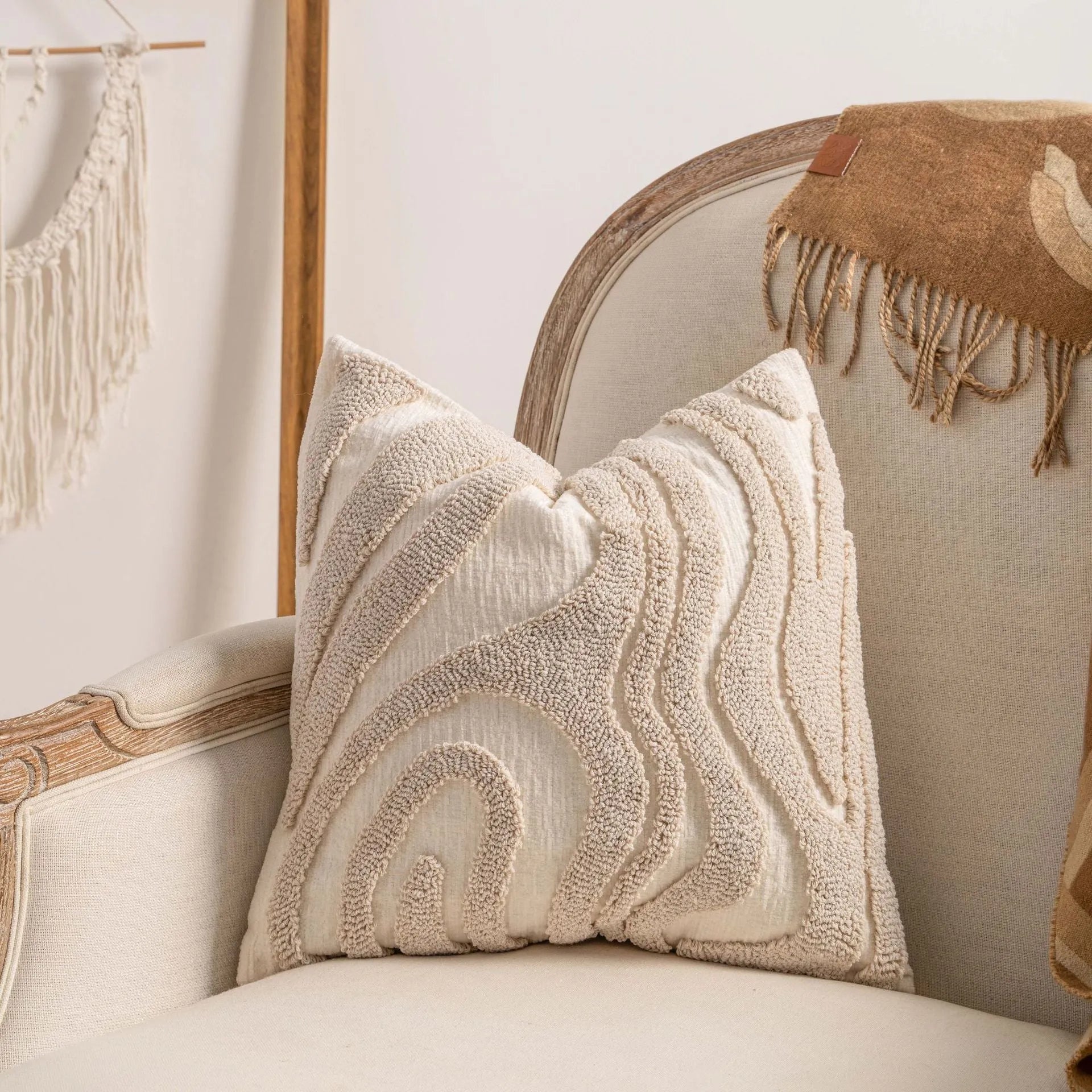 Knitted cushion cover with tassel fringe in a patterned design, shown on a sofa.