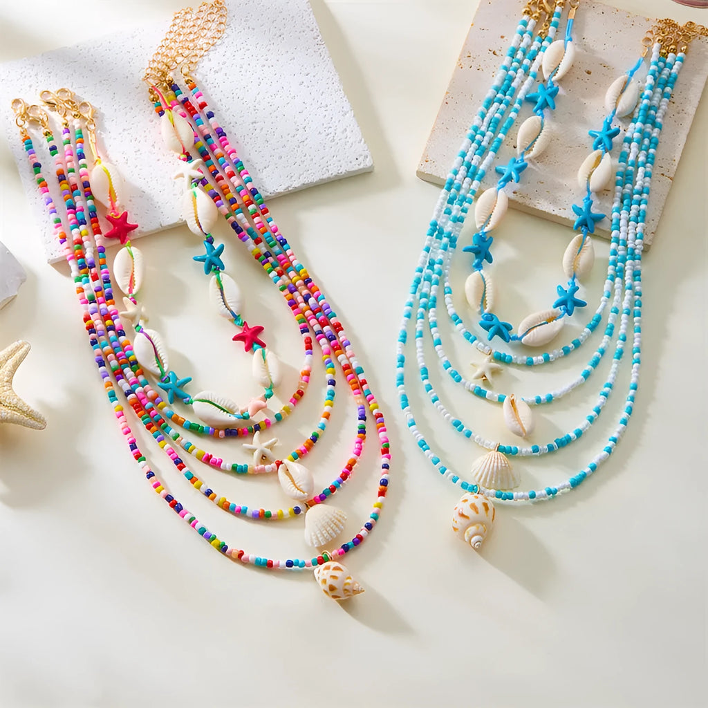 Five-piece women's necklace set with blue electroplated starfish, shell, and conch bead pendants on adjustable alloy chains.