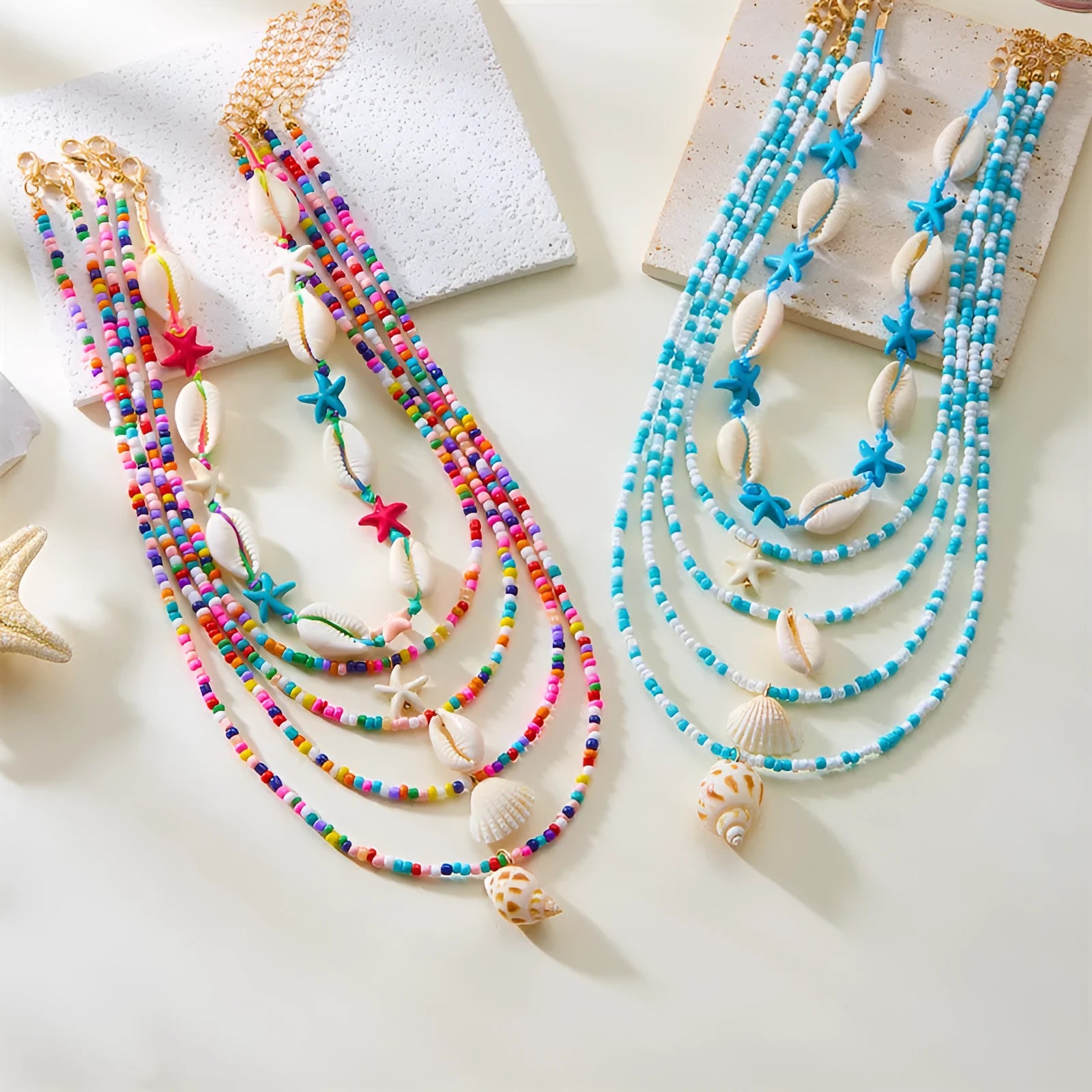 Five-piece women's necklace set with blue electroplated starfish, shell, and conch bead pendants on adjustable alloy chains.
