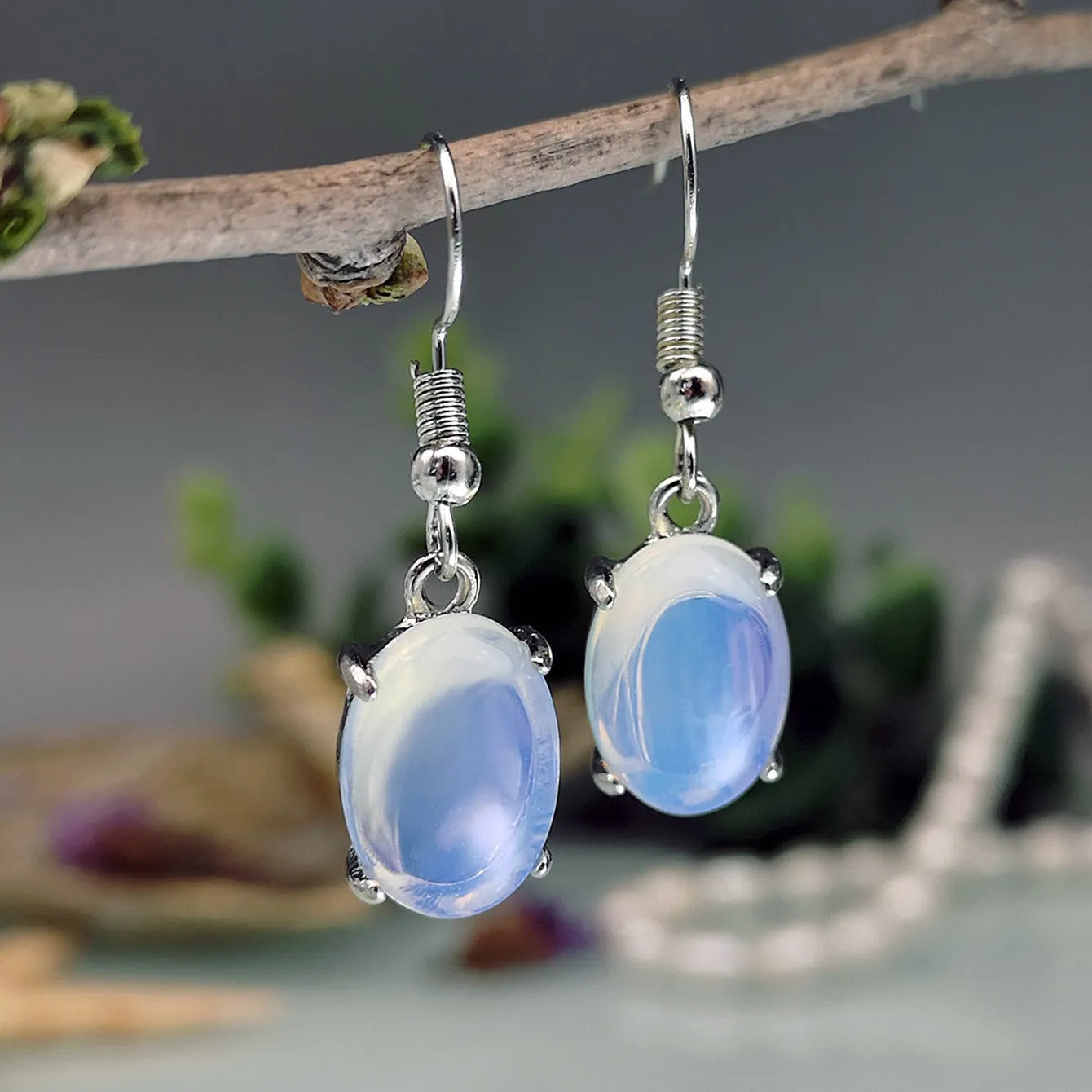 A pair of alloy drop earrings with a moonlight opal electroplated finish and a retro cross design within an ellipse shape.