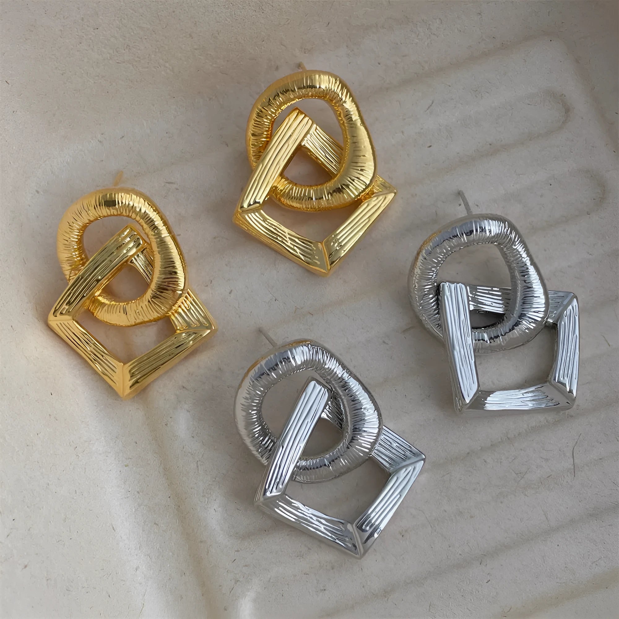 A pair of geometric circle drop earrings with a gold electroplated finish, showing a 3.4cm pendant length.