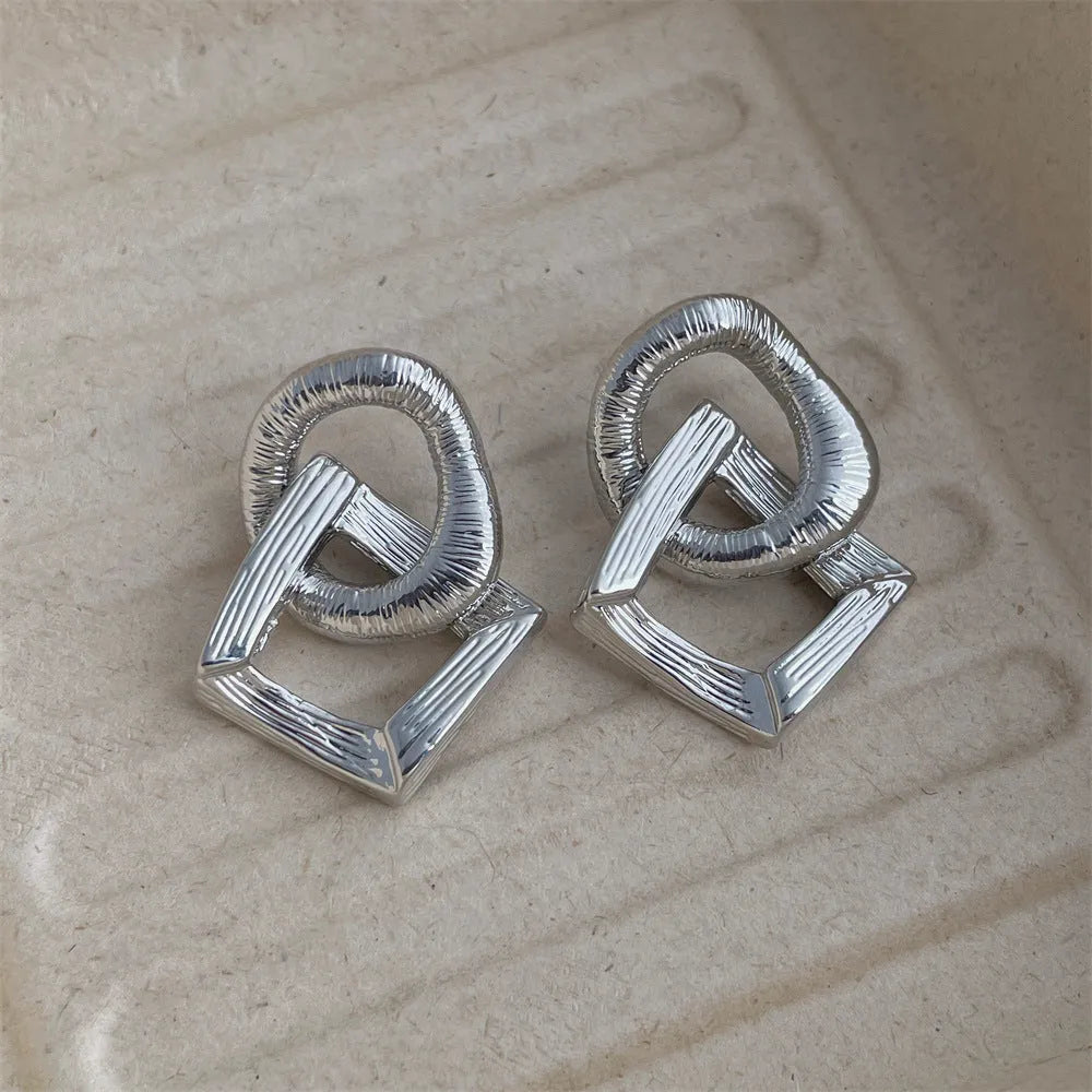 A pair of geometric circle drop earrings with a gold electroplated finish, showing a 3.4cm pendant length.