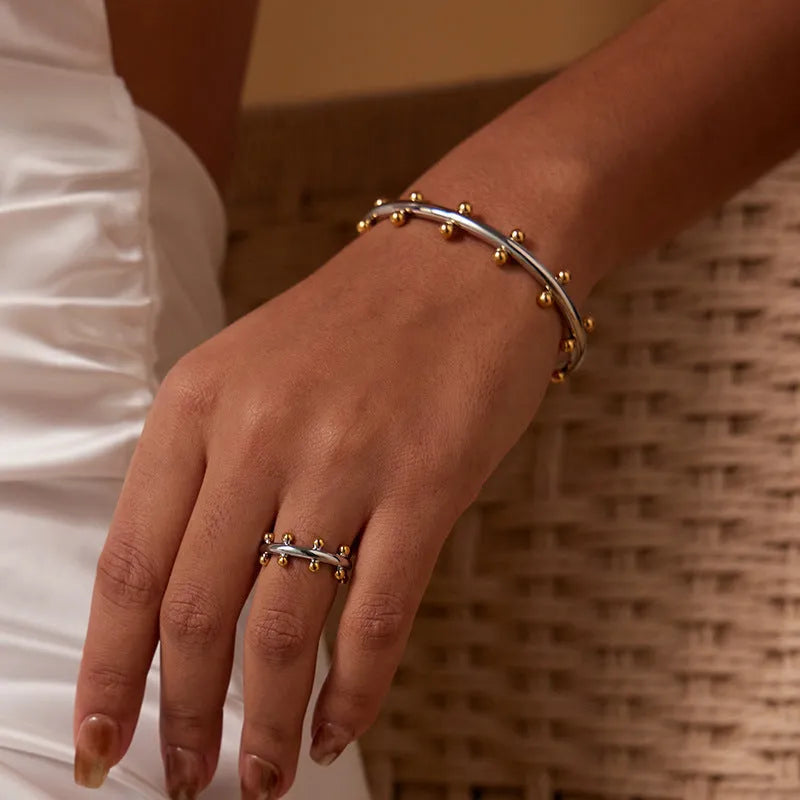 Stainless steel C-shaped bean bead bracelet with textured rivet finish on an alloy chain.