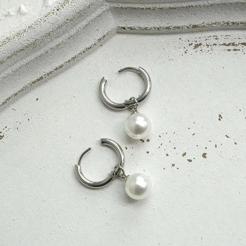 A pair of women's geometric round pearl drop earrings with a titanium steel finish and alloy construction.