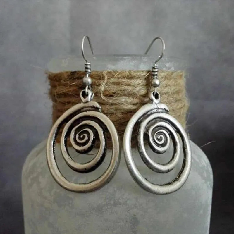 Silver geometric spiral earrings with distressed finish on white background