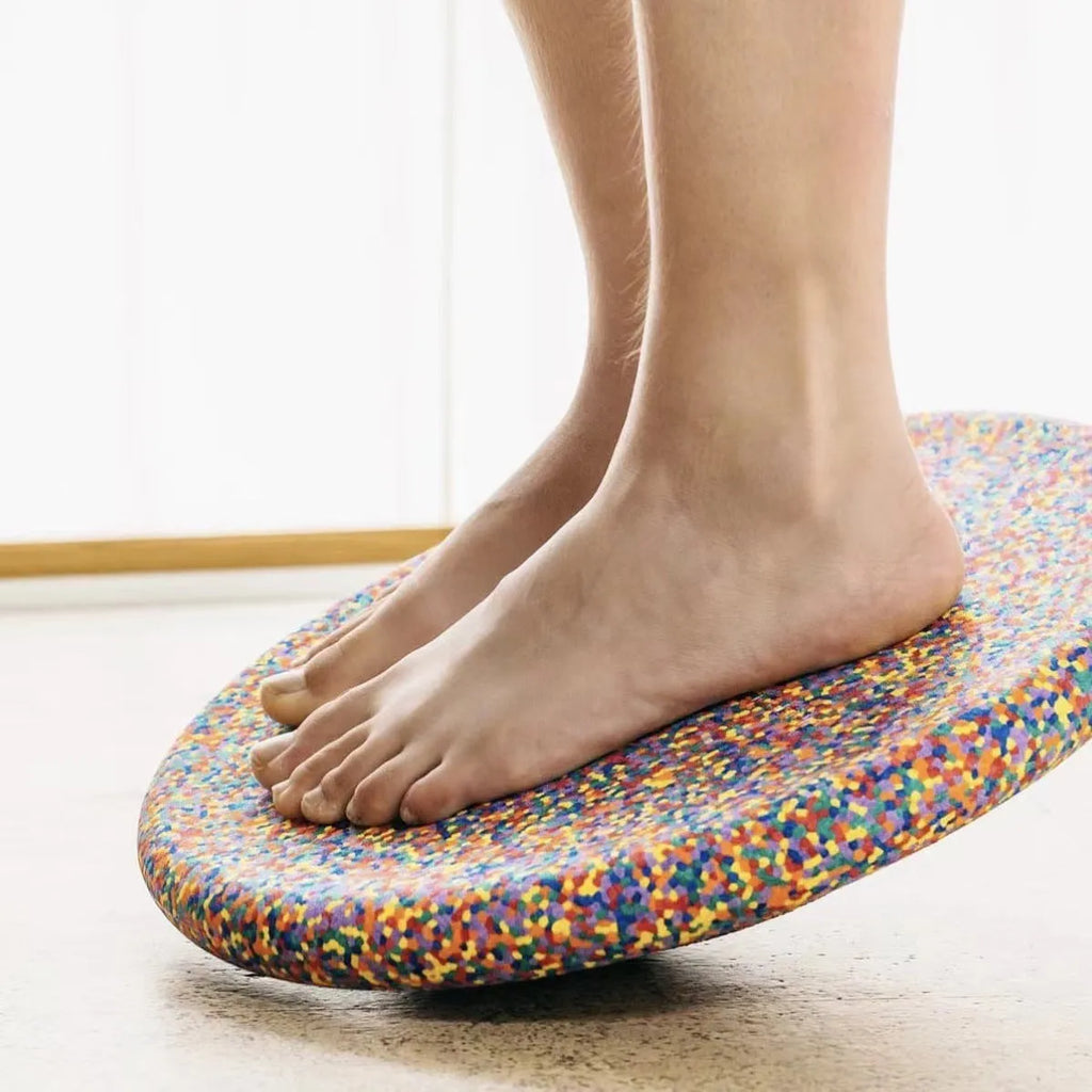 Plastic surfboard-shaped balance board for children, shown in mixed wood colour and black options.