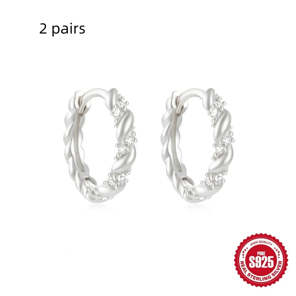A pair of small, round, geometric stud earrings made of sterling silver with an electroplated finish.