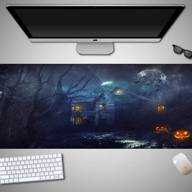 Oversized black Halloween-themed mouse pad with spooky artwork on a desk next to a gaming mouse.