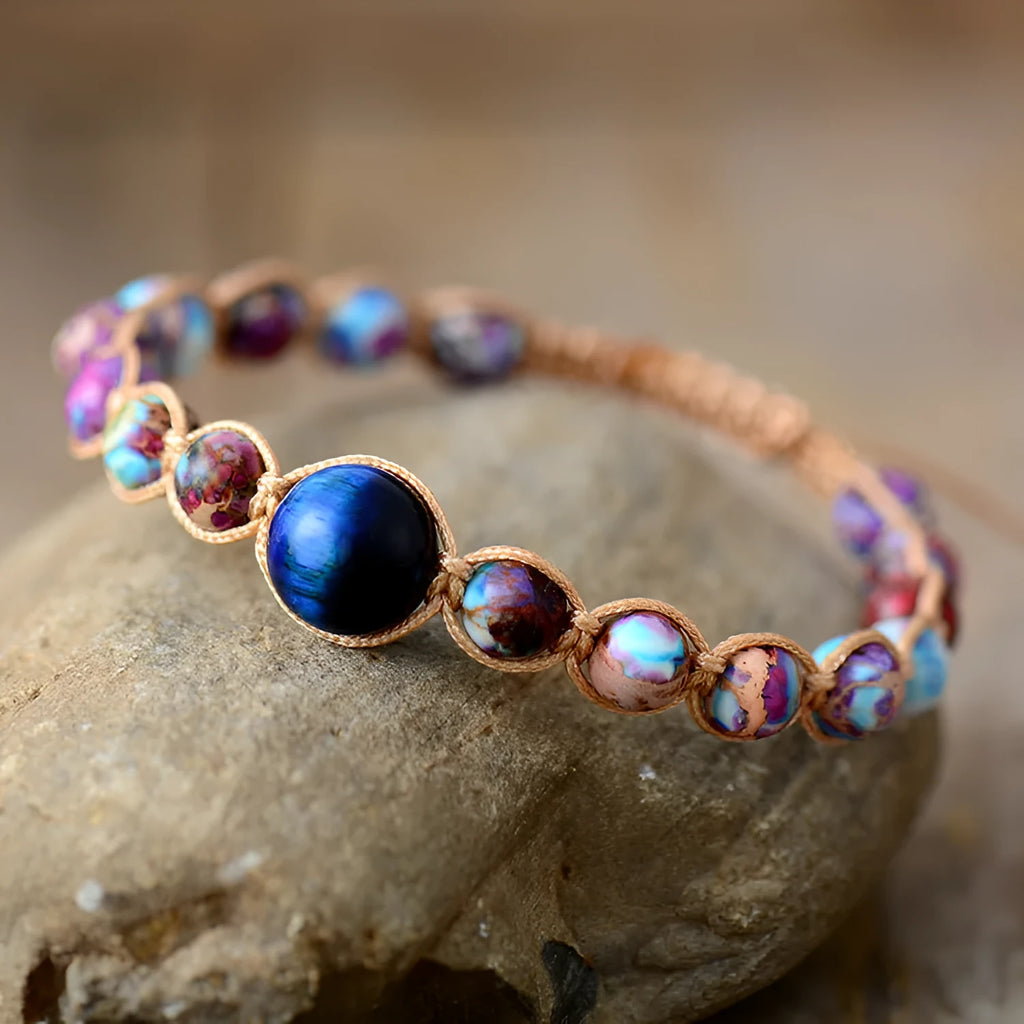 Hand woven friendship bracelet with adjustable cord and single Emperor Stone bead on a plain background.