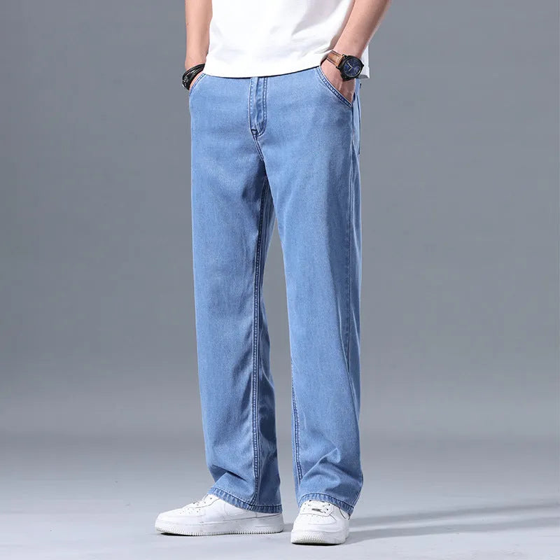 Man wearing light blue loose straight-leg lyocell jeans on a casual background.