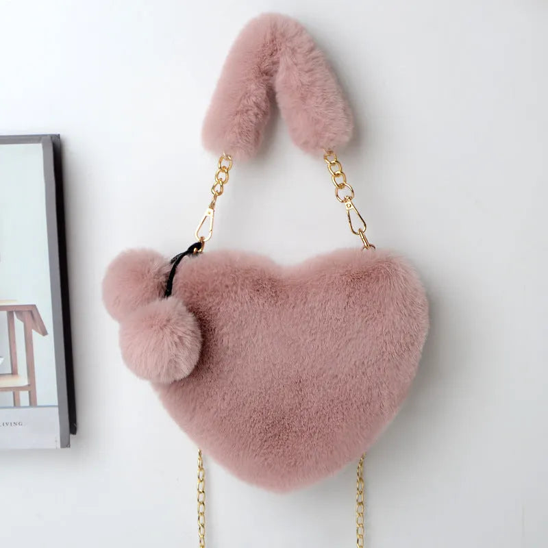 A soft, heart-shaped plush handbag for women in a medium size with a detachable shoulder strap.