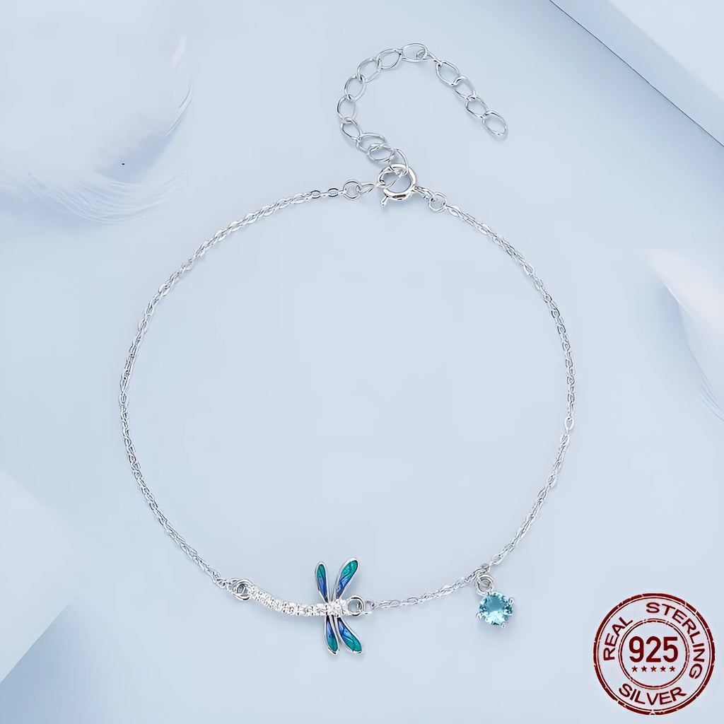 Sterling silver white gold plated dragonfly bracelet with dripping cubic zirconia stones on a light background