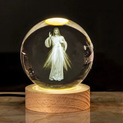 White crystal ball ornament on wood base with warm light and religious symbols