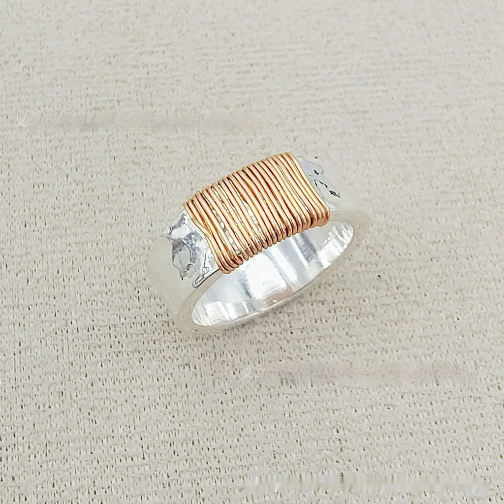 Geometric copper bracelet with irregular coil pattern forming silver-gold wide-faced ring design