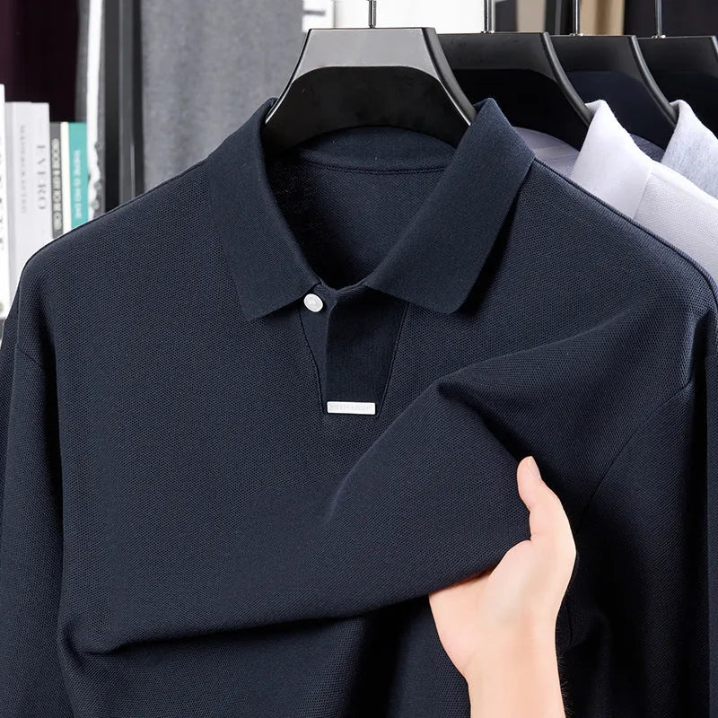 Man wearing a loose grey cotton polo shirt with a lapel collar and asymmetric design detail.