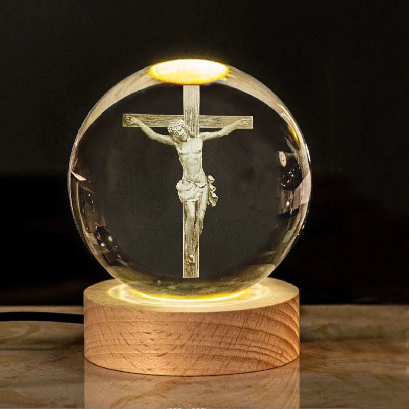 White crystal ball ornament on wood base with warm light and religious symbols