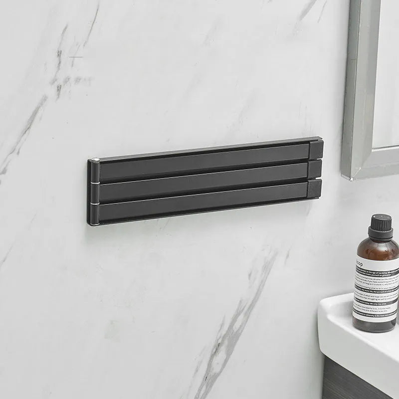 Nordic folding towel bar in black mounted on bathroom wall with towels hanging